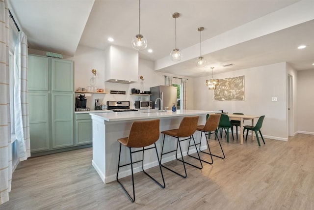306 Juarez St, San Marcos, TX 78666 - kitchen featuring custom range hood, stainless steel appliances, green cabinetry, an island with sink, and light wood-style flooring
