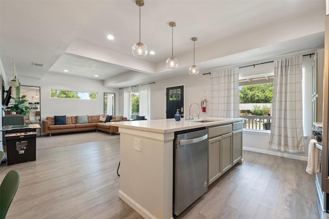 306 Juarez St, San Marcos, TX 78666 - kitchen featuring stainless steel dishwasher, a sink, light wood-style floors, light countertops, and a kitchen island with sink