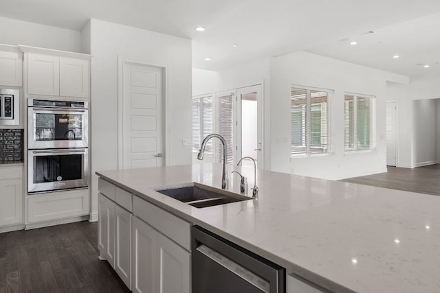 1928 Portobello Rd, Leander, TX 78641 - kitchen with stainless steel appliances, light stone counters, dark wood-style flooring, white cabinetry, and recessed lighting
