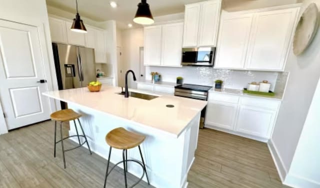 2593 Jack Nora Way, Round Rock, TX 78665 - kitchen featuring stainless steel appliances, a sink, light wood-style flooring, white cabinets, and a kitchen breakfast bar