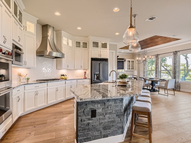 240 Townes Ct, Dripping Springs, TX 78620 - kitchen with appliances with stainless steel finishes, wall chimney exhaust hood, light wood finished floors, light stone countertops, and recessed lighting
