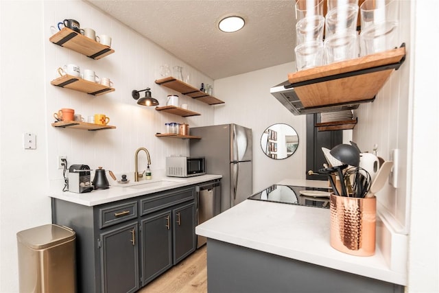 311 Quarry St, San Marcos, TX 78666 - kitchen featuring open shelves, a sink, light wood-style floors, a textured ceiling, and light countertops