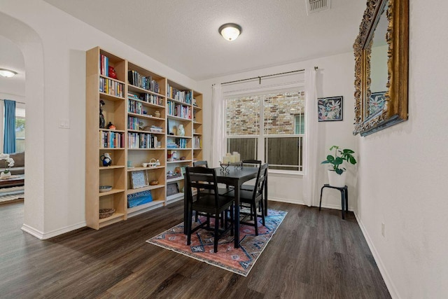 209 Sage Derby Dr, Hutto, TX 78634 - dining area featuring dark wood finished floors, arched walkways, baseboards, healthy amount of natural light, and a textured ceiling