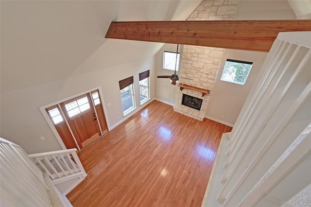 1502 Medio Calle, Austin, TX 78733 - unfurnished living room with high vaulted ceiling, light wood-type flooring, a stone fireplace, and ceiling fan