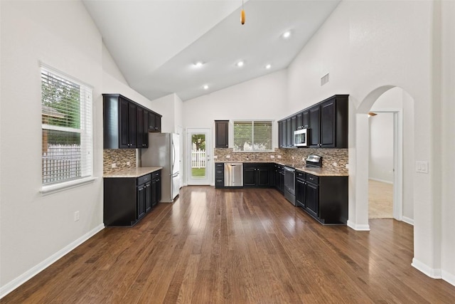 711 Rolling Oak Dr Unit 106, Round Rock, TX 78664 - kitchen featuring stainless steel appliances, tasteful backsplash, arched walkways, dark wood-style flooring, and high vaulted ceiling