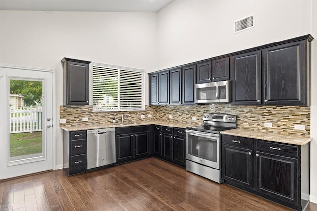 711 Rolling Oak Dr Unit 106, Round Rock, TX 78664 - kitchen featuring stainless steel appliances, dark cabinets, healthy amount of natural light, and a towering ceiling