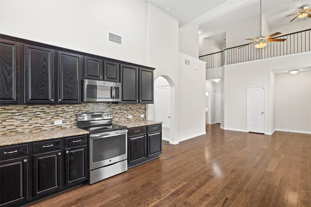 711 Rolling Oak Dr Unit 106, Round Rock, TX 78664 - kitchen featuring stainless steel appliances, a towering ceiling, ceiling fan, dark cabinets, and arched walkways