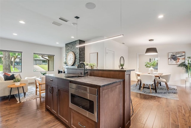 2502 Spring Creek Dr, Austin, TX 78704 - kitchen featuring a sink, stainless steel microwave, light wood-type flooring, dark countertops, and recessed lighting