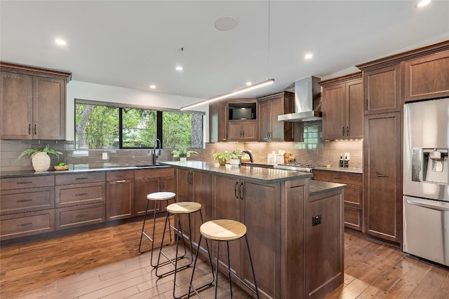 2502 Spring Creek Dr, Austin, TX 78704 - kitchen with stainless steel fridge, wall chimney exhaust hood, wood-type flooring, a center island, and recessed lighting