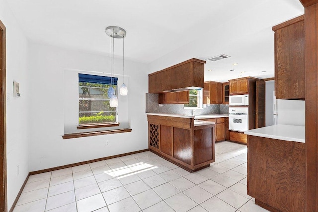 2305 Preston Trails Cv, Austin, TX 78747 - kitchen featuring white appliances, brown cabinetry, a peninsula, decorative backsplash, and light tile patterned floors