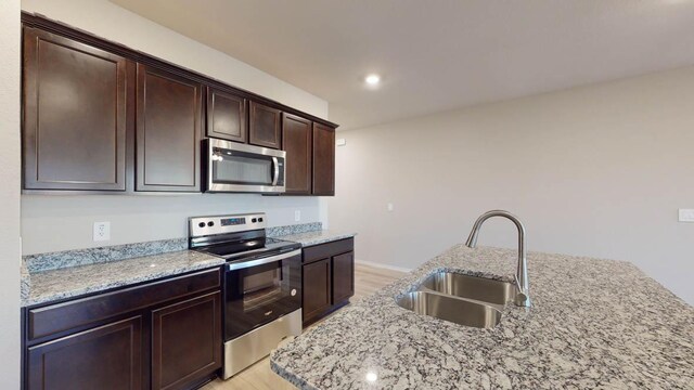 1310 Merritt St, Temple, TX 76504 - kitchen featuring appliances with stainless steel finishes, a sink, light wood-style floors, and dark brown cabinetry