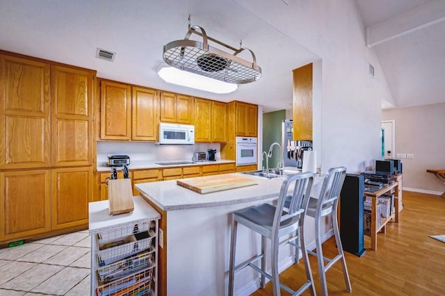 1231 Montell Rd, Wimberley, TX 78676 - kitchen featuring white appliances, a sink, light countertops, a peninsula, and brown cabinetry