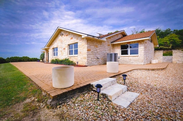 1231 Montell Rd, Wimberley, TX 78676 - back of house with stone siding, a patio, and central AC unit