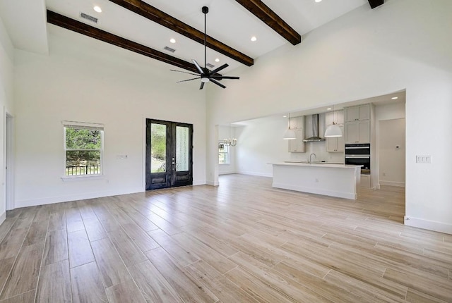 2803 Wilson Ave, Lago Vista, TX 78645 - unfurnished living room featuring plenty of natural light, a high ceiling, ceiling fan, beam ceiling, and light wood finished floors