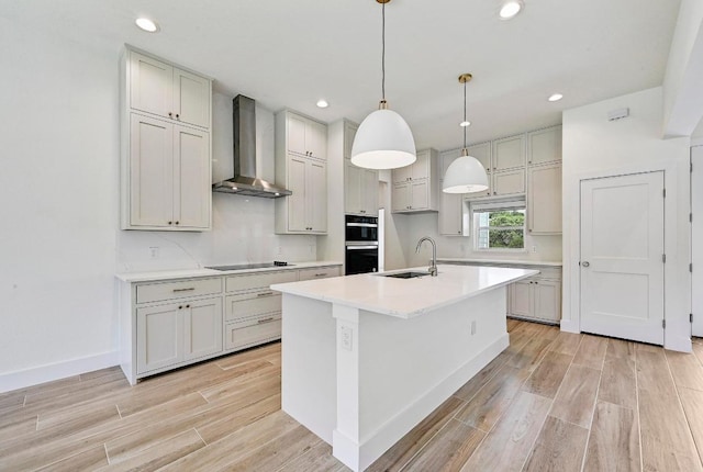 2803 Wilson Ave, Lago Vista, TX 78645 - kitchen featuring wall chimney exhaust hood, stainless steel double oven, light wood-style flooring, black electric cooktop, and a kitchen island with sink