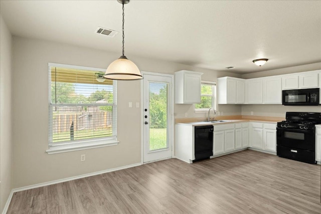 15411 Ora Ln, Pflugerville, TX 78660 - kitchen with black appliances, light wood finished floors, light countertops, white cabinets, and decorative light fixtures