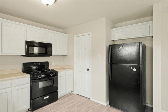 15411 Ora Ln, Pflugerville, TX 78660 - kitchen with black appliances, light wood-type flooring, light countertops, and white cabinetry