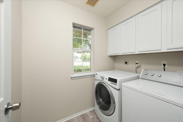 15411 Ora Ln, Pflugerville, TX 78660 - laundry area featuring cabinet space, washing machine and dryer, and light wood finished floors
