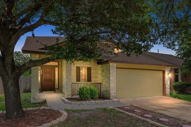 15411 Ora Ln, Pflugerville, TX 78660 - view of front facade with stone siding, an attached garage, concrete driveway, and covered porch