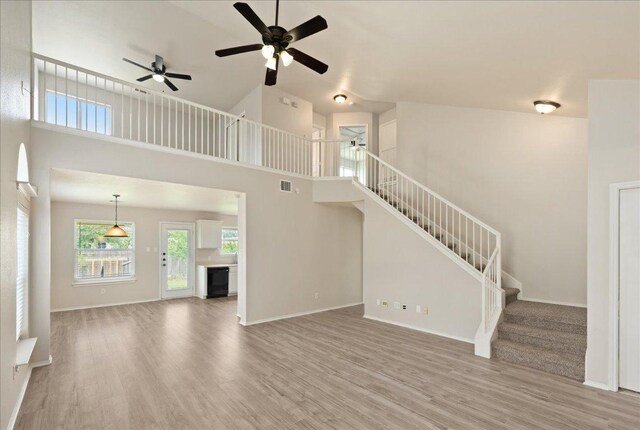 15411 Ora Ln, Pflugerville, TX 78660 - unfurnished living room with wood finished floors, a ceiling fan, stairs, and a high ceiling