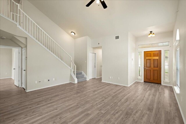 15411 Ora Ln, Pflugerville, TX 78660 - unfurnished living room with wood finished floors, a towering ceiling, a ceiling fan, and stairs