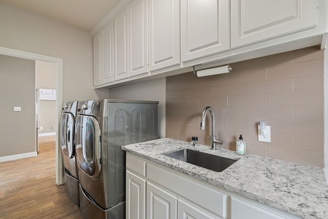 212 Lakefront Dr, Point Venture, TX 78645 - laundry room with washing machine and clothes dryer, light wood-style flooring, cabinet space, and baseboards