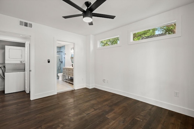 48 Chicon St, Austin, TX 78702 - unfurnished bedroom featuring stacked washer and clothes dryer, baseboards, dark wood finished floors, ensuite bathroom, and ceiling fan