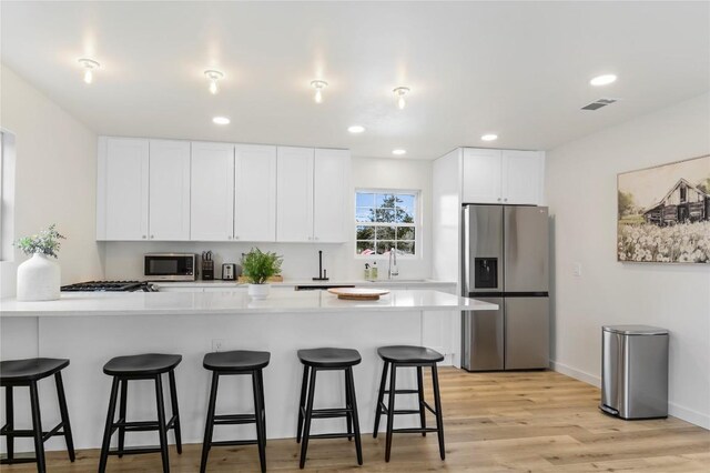 10226 Parsons Rd, Manor, TX 78653 - kitchen with stainless steel appliances, a sink, a kitchen breakfast bar, white cabinetry, and a peninsula
