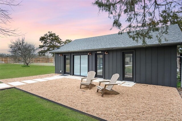 10226 Parsons Rd, Manor, TX 78653 - back of property at dusk with board and batten siding, roof with shingles, and a patio area
