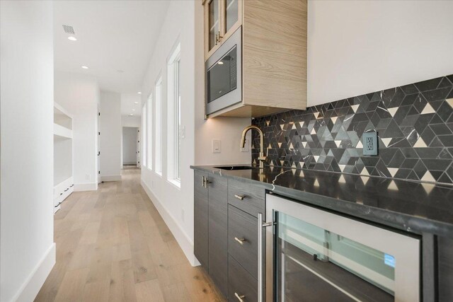 98 Wennmohs Pl, Horseshoe Bay, TX 78657 - indoor wet bar featuring wine cooler, stainless steel microwave, tasteful backsplash, light wood finished floors, and recessed lighting