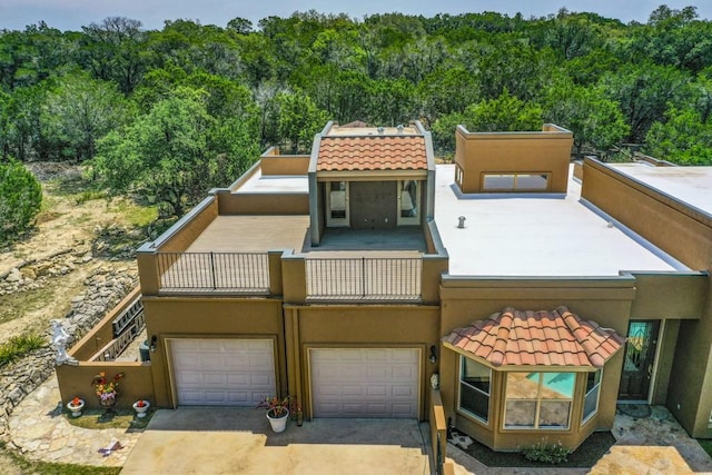 3211 Constitution Dr, Lago Vista, TX 78645 - view of front facade featuring stucco siding, a tile roof, a garage, and a view of trees
