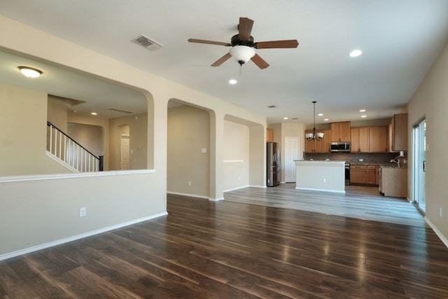 1244 Yellow Iris Rd, Leander, TX 78641 - unfurnished living room featuring ceiling fan, dark wood-style floors, arched walkways, recessed lighting, and stairs