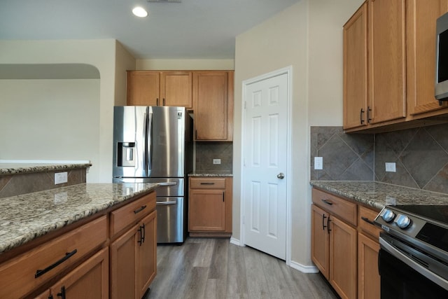 1244 Yellow Iris Rd, Leander, TX 78641 - kitchen with appliances with stainless steel finishes, light wood-style floors, light stone countertops, and decorative backsplash