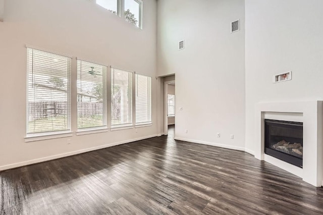 461 Constitution Way, Kyle, TX 78640 - unfurnished living room with a high ceiling, dark wood-style floors, baseboards, and a glass covered fireplace