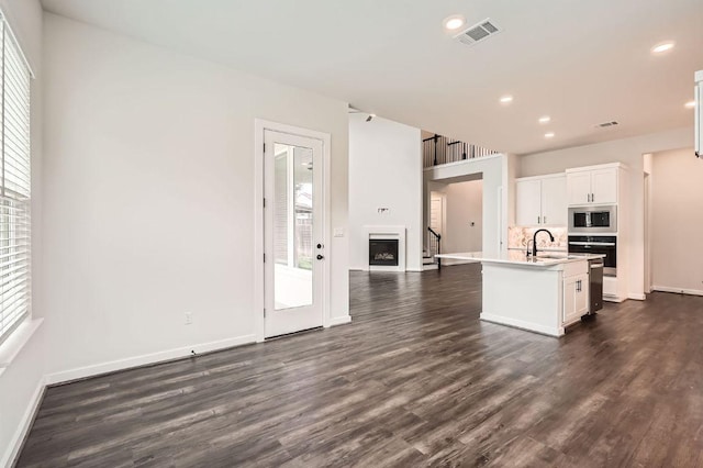 461 Constitution Way, Kyle, TX 78640 - kitchen with stainless steel microwave, a fireplace, oven, dark wood finished floors, and light countertops