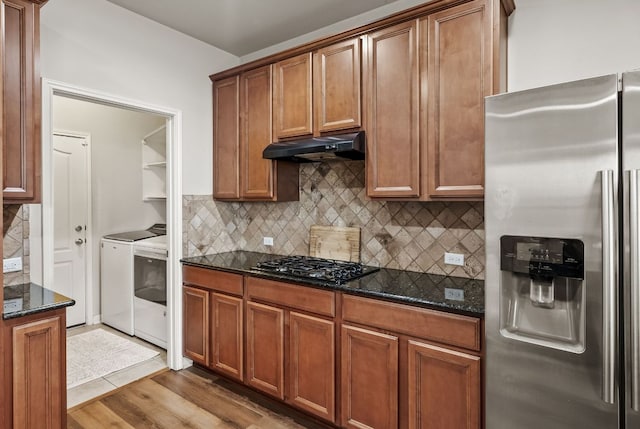 4404 Cierne Cv, Round Rock, TX 78681 - kitchen featuring stainless steel fridge, washing machine and dryer, under cabinet range hood, black gas stovetop, and dark stone counters