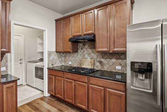 4404 Cierne Cv, Round Rock, TX 78681 - kitchen featuring stainless steel fridge, washing machine and dryer, under cabinet range hood, black gas cooktop, and dark stone countertops