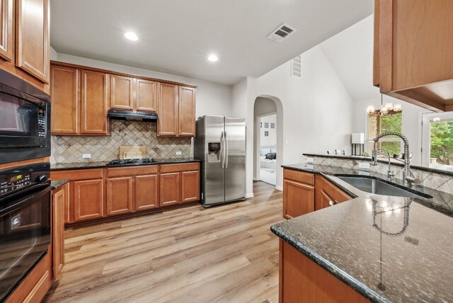 4404 Cierne Cv, Round Rock, TX 78681 - kitchen with black appliances, a sink, arched walkways, light wood-type flooring, and tasteful backsplash