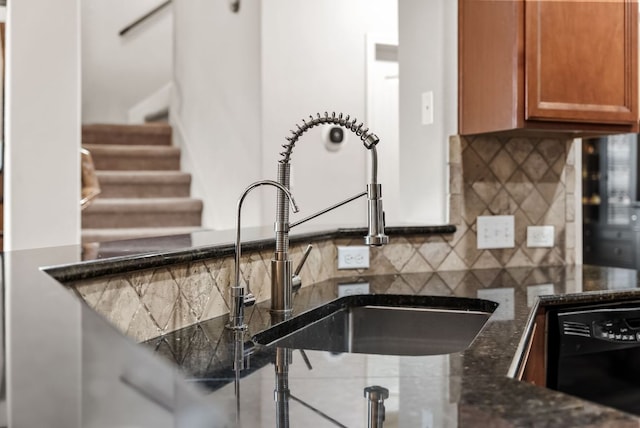 4404 Cierne Cv, Round Rock, TX 78681 - kitchen with black dishwasher, a sink, backsplash, brown cabinetry, and dark stone countertops