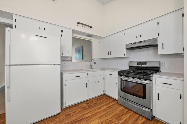 5808 Cedardale Dr, Austin, TX 78745 - kitchen with freestanding refrigerator, stainless steel range with gas stovetop, under cabinet range hood, a sink, and white cabinets