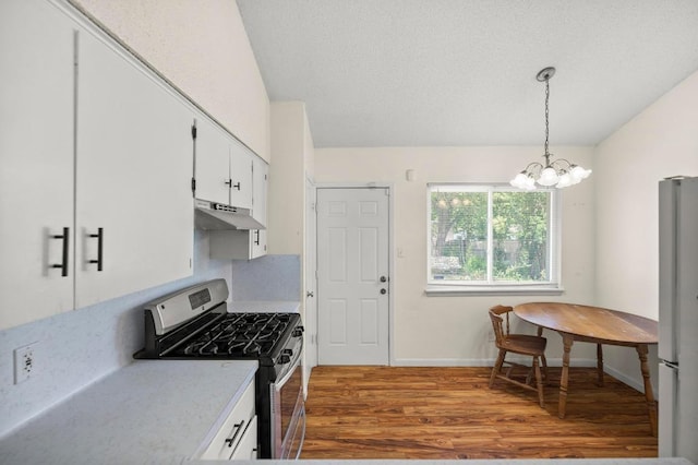 5808 Cedardale Dr, Austin, TX 78745 - kitchen featuring stainless steel gas range, under cabinet range hood, freestanding refrigerator, wood finished floors, and light countertops