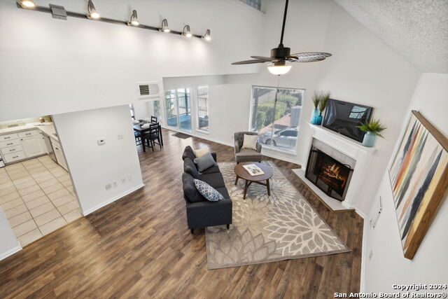2918 Ranch Road 620th Rd N Unit C122, Austin, TX 78734 - living area featuring a warm lit fireplace, a ceiling fan, wood finished floors, a textured ceiling, and high vaulted ceiling