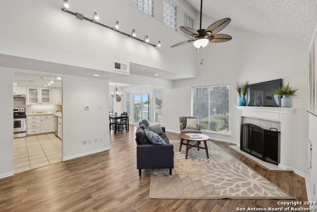 2918 Ranch Road 620th Rd N Unit C122, Austin, TX 78734 - living room with a tiled fireplace, ceiling fan, high vaulted ceiling, light wood-style floors, and a chandelier