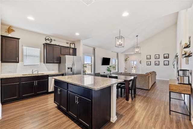 208 Shiner Ln, Georgetown, TX 78626 - kitchen featuring stainless steel appliances, a sink, vaulted ceiling, light wood finished floors, and a center island