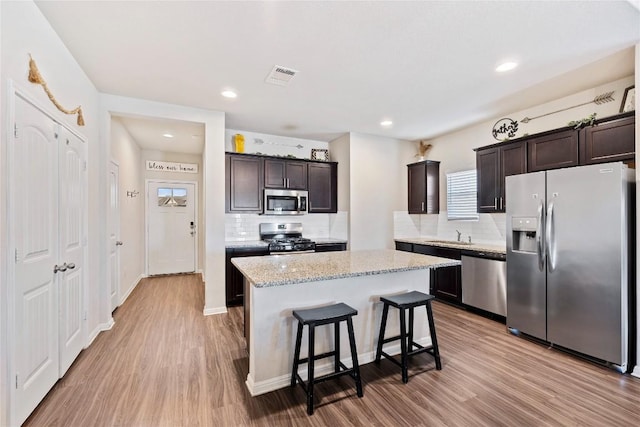 208 Shiner Ln, Georgetown, TX 78626 - kitchen featuring appliances with stainless steel finishes, tasteful backsplash, light wood-style flooring, dark brown cabinets, and recessed lighting