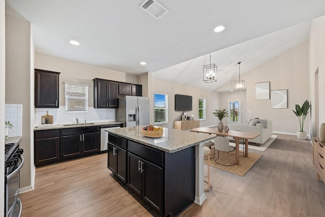 208 Shiner Ln, Georgetown, TX 78626 - kitchen with appliances with stainless steel finishes, decorative backsplash, light wood-type flooring, a center island, and light stone counters
