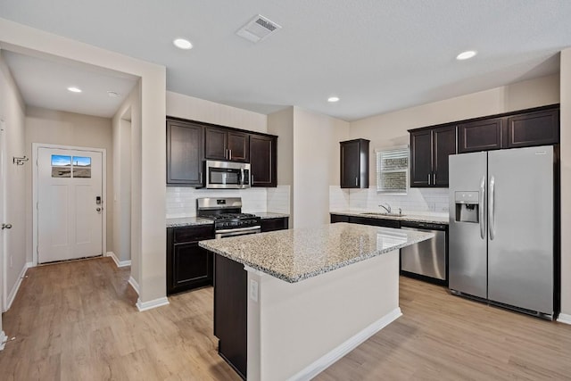 208 Shiner Ln, Georgetown, TX 78626 - kitchen with appliances with stainless steel finishes, backsplash, light stone counters, light wood-style flooring, and recessed lighting