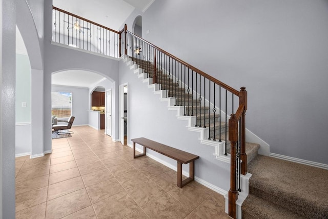 2817 Dusty Chisolm Trl, Pflugerville, TX 78660 - stairs with arched walkways, tile patterned flooring, baseboards, and a towering ceiling