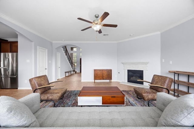 2817 Dusty Chisolm Trl, Pflugerville, TX 78660 - living room featuring arched walkways, ceiling fan, crown molding, baseboards, and a glass covered fireplace
