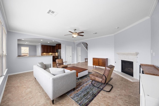 2817 Dusty Chisolm Trl, Pflugerville, TX 78660 - living room with arched walkways, a glass covered fireplace, ceiling fan, light tile patterned floors, and crown molding